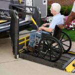 A non-emergency medical transportation representative is loading a wheel chair customer into a medical transportation vehicle.